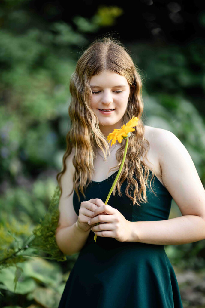 Teen girl at Rockway Gardens holding a flower during portrait session in Kitchener-Waterloo.