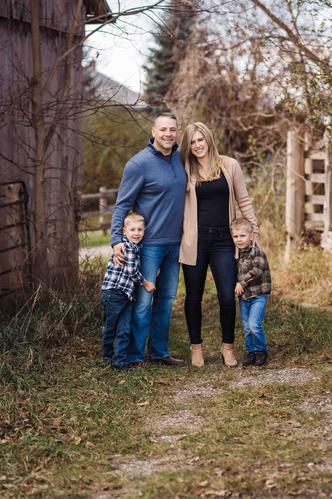 family standing beside barn for fall photos in Kitchener-Waterloo