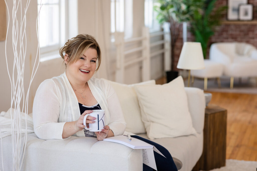 Kitchener-Waterloo photographer, Kendra of Portraits by Kendra, sitting on a couch, smiling