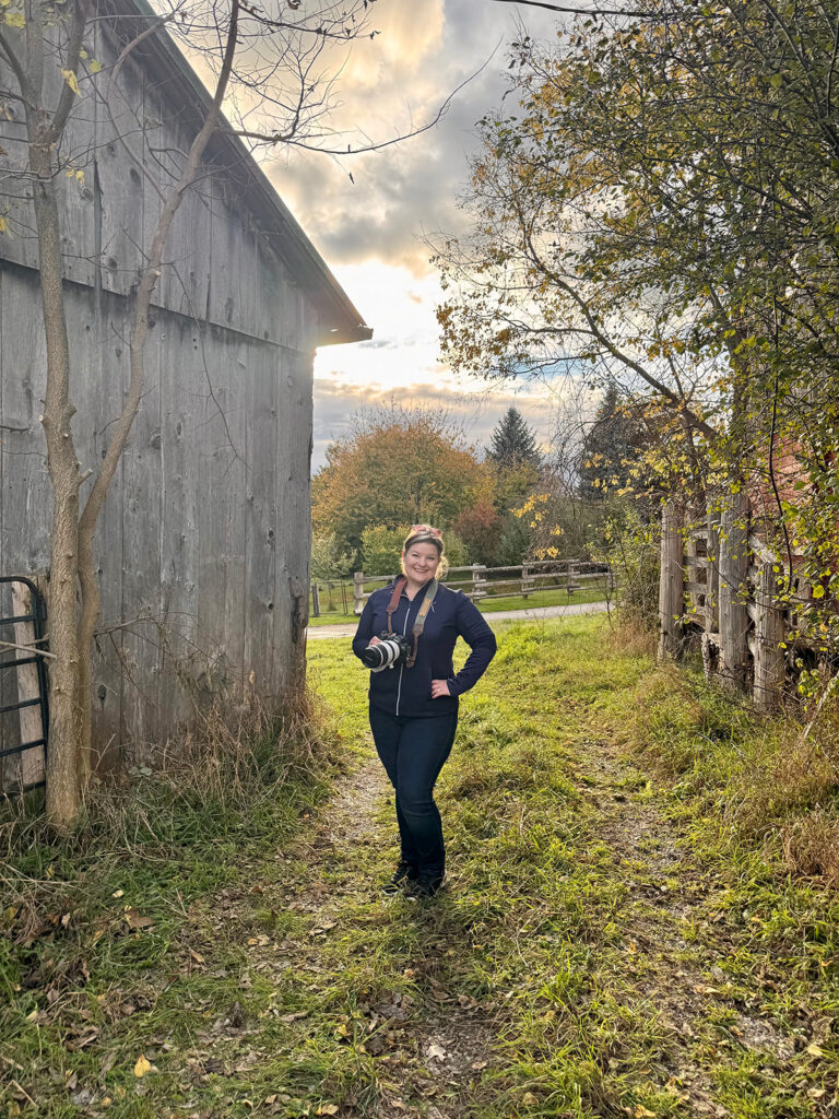 Kitchener-Waterloo photographer, Kendra, of Portraits by Kendra, standing outdoors with her camera during a fall portrait session.