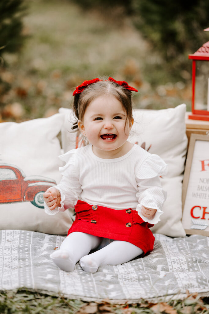 Little girl laughing during holiday mini photo session at Chickadee Tree Farm featuring warm family moments among the Christmas trees — captured by Portraits by Kendra, Kitchener-Waterloo family photographer.
