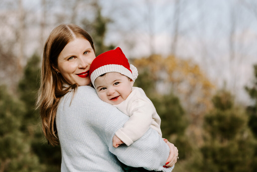 Photo of Mom and baby taken during holiday mini photo session at Chickadee Tree Farm featuring warm family moments among the Christmas trees — captured by Portraits by Kendra, Kitchener-Waterloo family photographer.