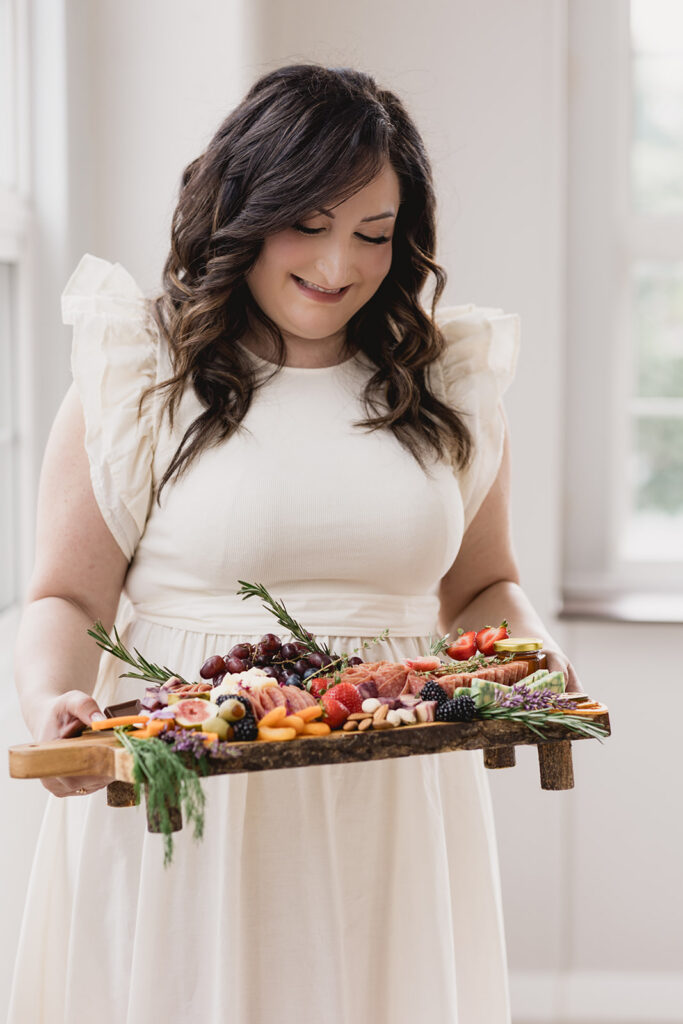 Mary Tchabrazian, owner of Marycuterie, holding a charcuterie board during a branding photoshoot by Portraits by Kendra in Waterloo Region