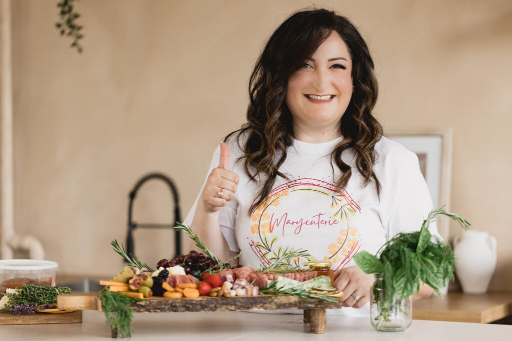 Mary Tchabrazian, owner of Marycuterie, giving the thumbs up after making a charcuterie board during a branding photoshoot by Portraits by Kendra in Waterloo Region