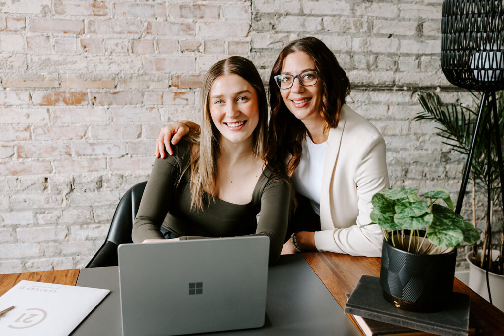 Photo of the The Livingston Team sitting at a desk during a Mother-Daughter Branding Session at West Haus Studio in Downtown Kitchener, taken by Portraits by Kendra