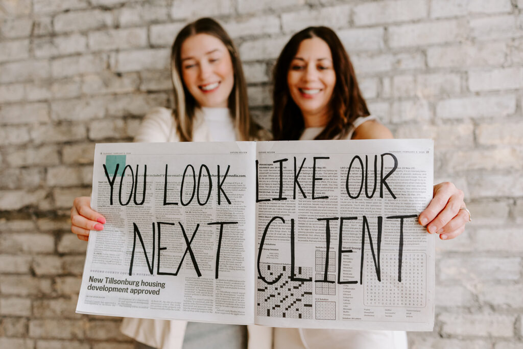 Photo of the The Livingston Team holding a sign during a Mother-Daughter Branding Session at West Haus Studio in Downtown Kitchener, taken by Portraits by Kendra