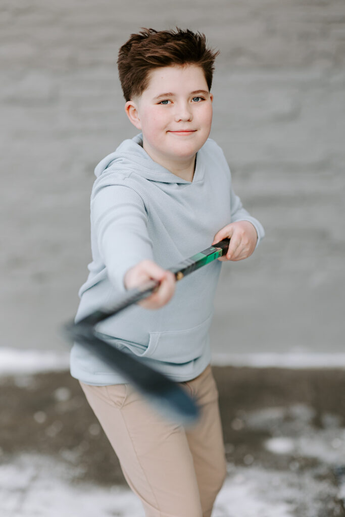Portrait of a teen boy holding his hockey stick.  Photo taken by Portraits by Kendra in Kitchener-Waterloo