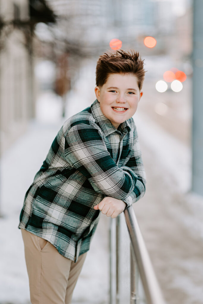 Relaxed teen boy leaning against a railing outside in Kitchener-Waterloo. Photo taken by Portraits by Kendra