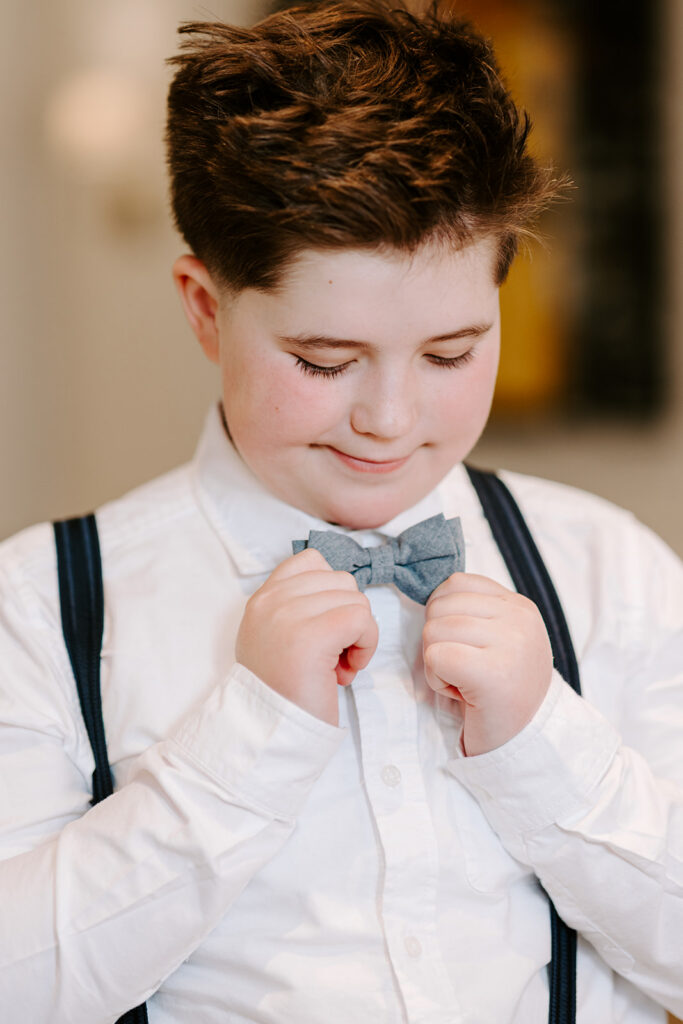 Photo of a teen boy is fixing his bow tie. Photo taken in Kitchener-Waterloo by Portraits by Kendra