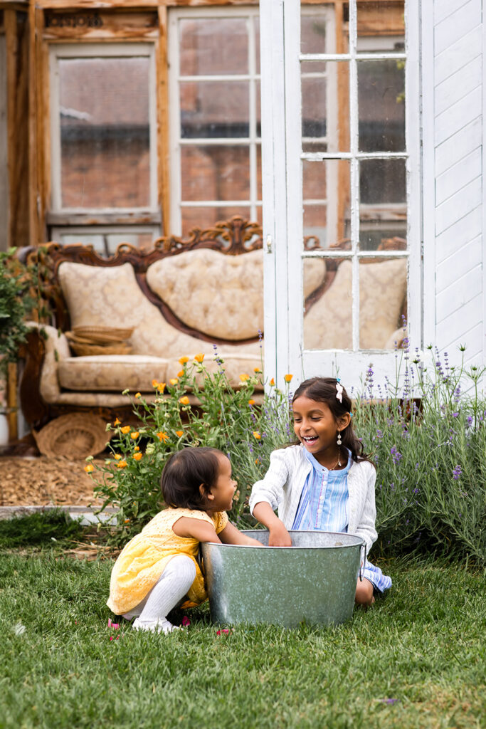 Photo of two little sisters sitting on the grass taken by Portraits by Kendra Photography in Kitchener-Waterloo