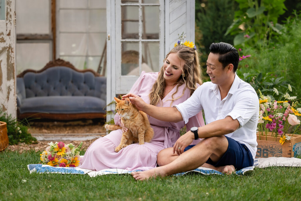 Photo of a couple and their cat sitting on a blanket  taken by Portraits by Kendra Photography at a Spring mini session