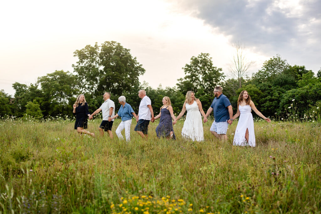 Photo of extended famiy standing in a field taken by Portraits by Kendra during a Fall family photography session in Kitchener-Waterloo