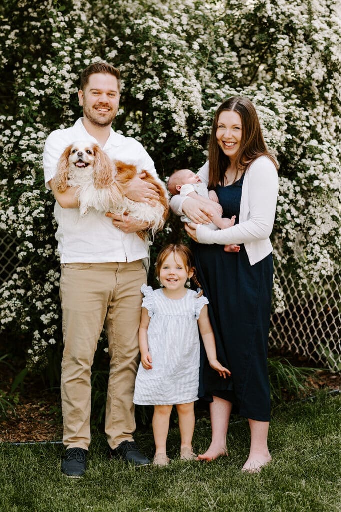 Lifestyle family newborn session outside at home in Kitchener-Waterloo, mom, dad and sibling with newborn baby and family dog.