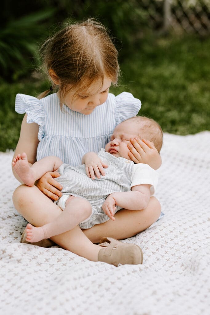 Lifestyle family newborn session outside in Kitchener-Waterloo, sibling holding newborn baby.