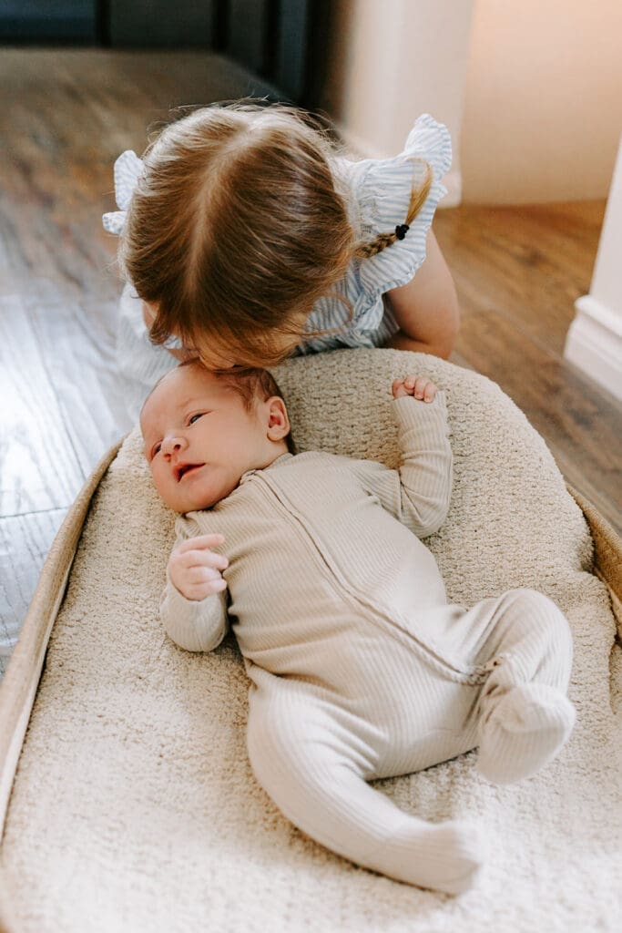 Lifestyle family newborn session at home in Kitchener-Waterloo, sibling kissing newborn baby.
