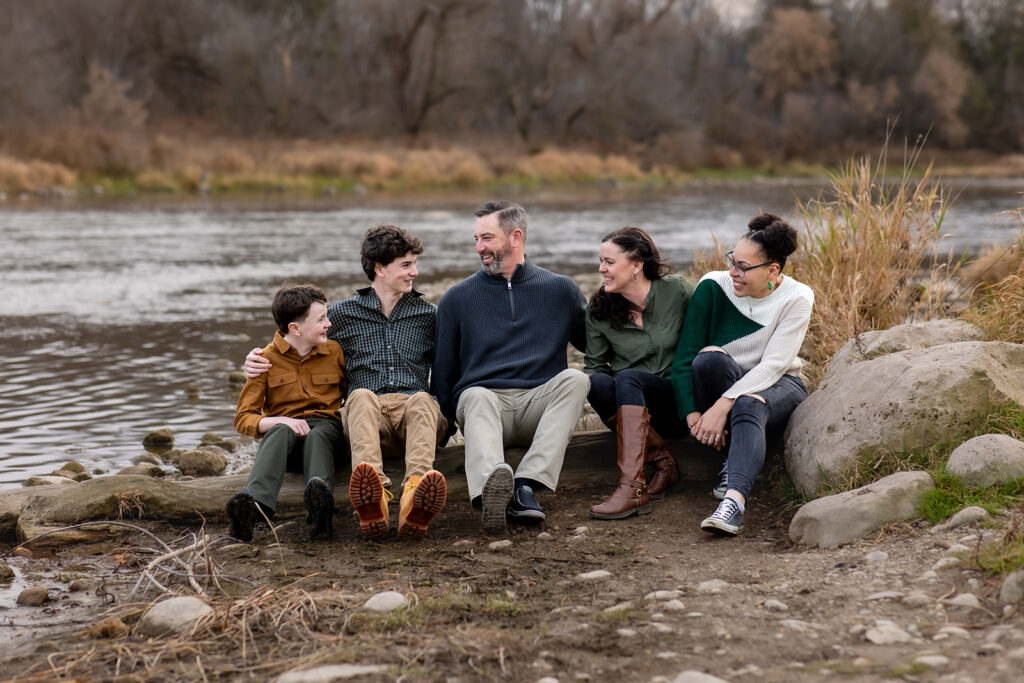 Family of five laughing together by the water during a relaxed outdoor family photo session in Kitchener-Waterloo.