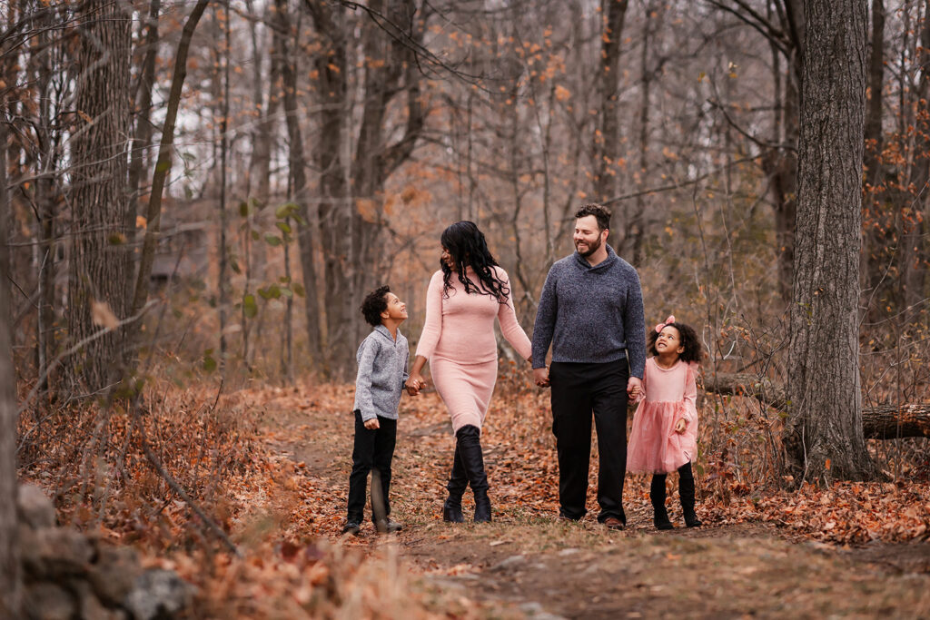 Family of four walking hand in hand through a wooded trail during a fall family photo session in Kitchener-Waterloo.